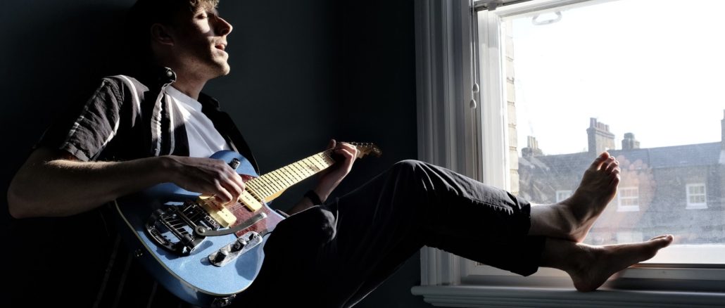 man sitting by the window playing the guitar