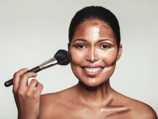 Close up portrait of contour and highlight makeup on female model. Woman applying makeup on her face with brush.