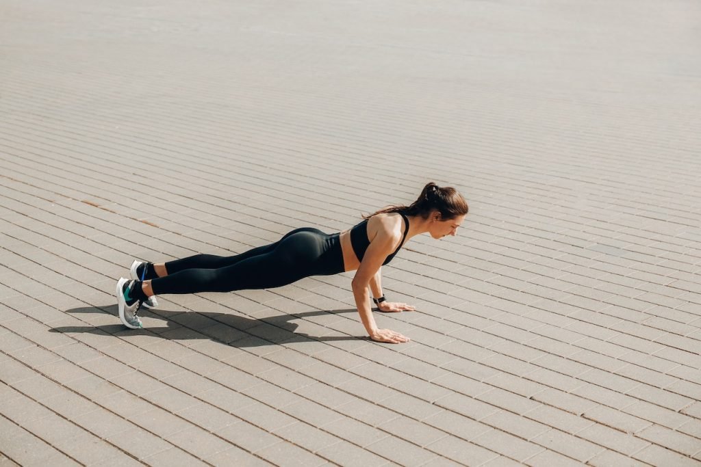 woman wearing sport bra and black legging doing press up