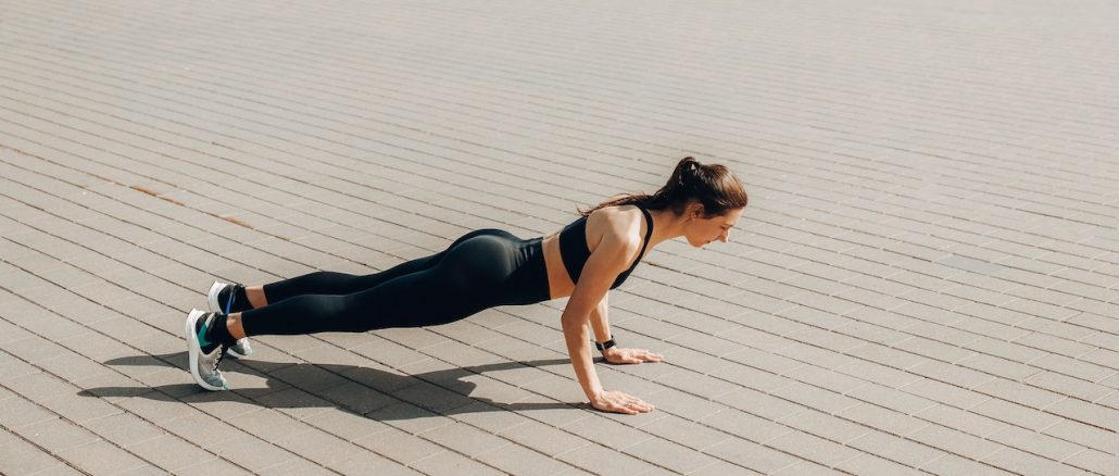 woman wearing sport bra and black legging doing press up