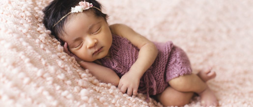 baby girl sleeping on pink bed