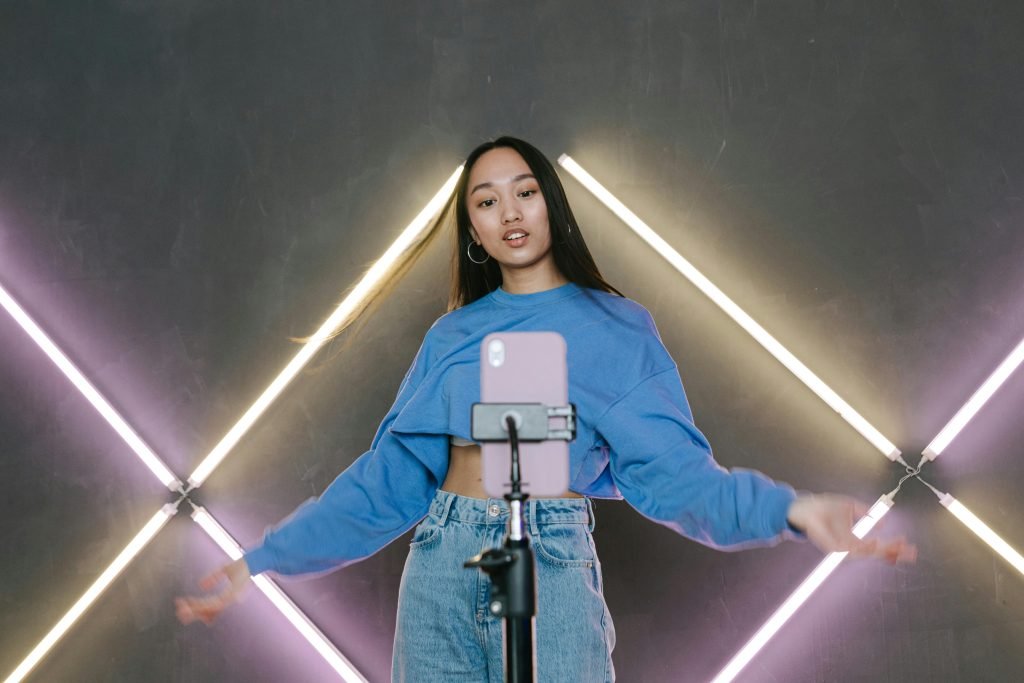 a-woman-in-blue-sweater-dancing-in-front-of-her-mobile-phone-on-a-tripod-7676486/