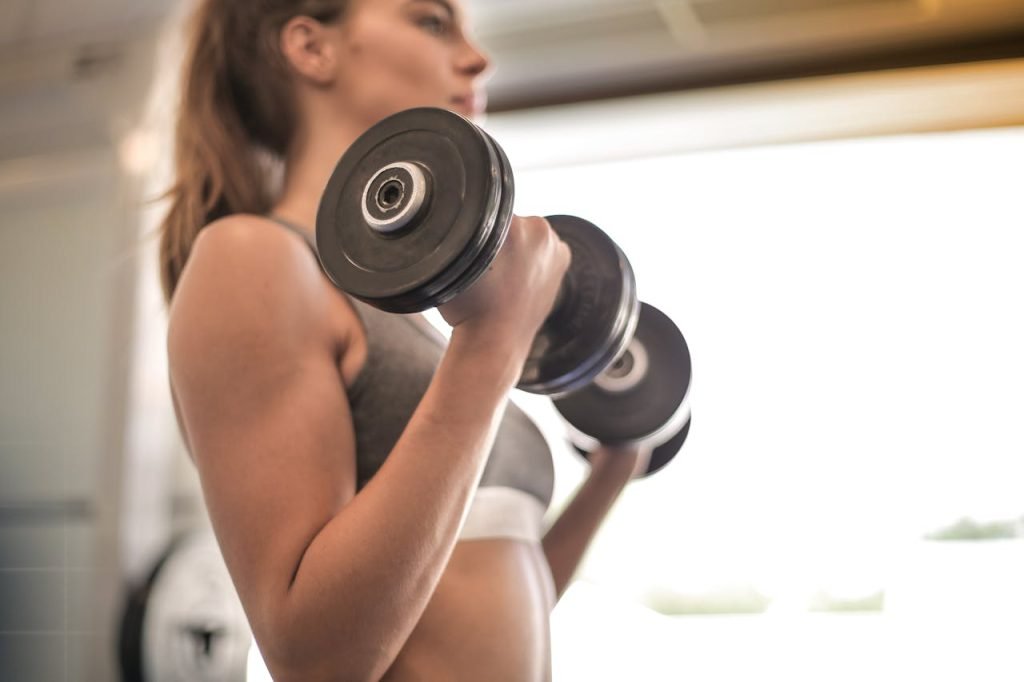 woman-in-gray-sports-bra-holding-black-dumbbell