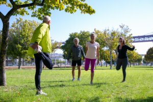 group-retired-active-mature-people-wearing-sports-clothes-doing-morning-exercise-park-grass-retirement-active-lifestyle-concept-scaled.