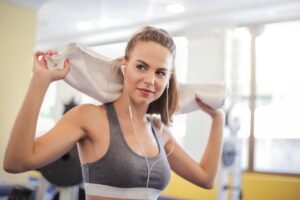 Woman at the gym listening to music and getting motivated by the 2025 Best Gym Songs Playlist