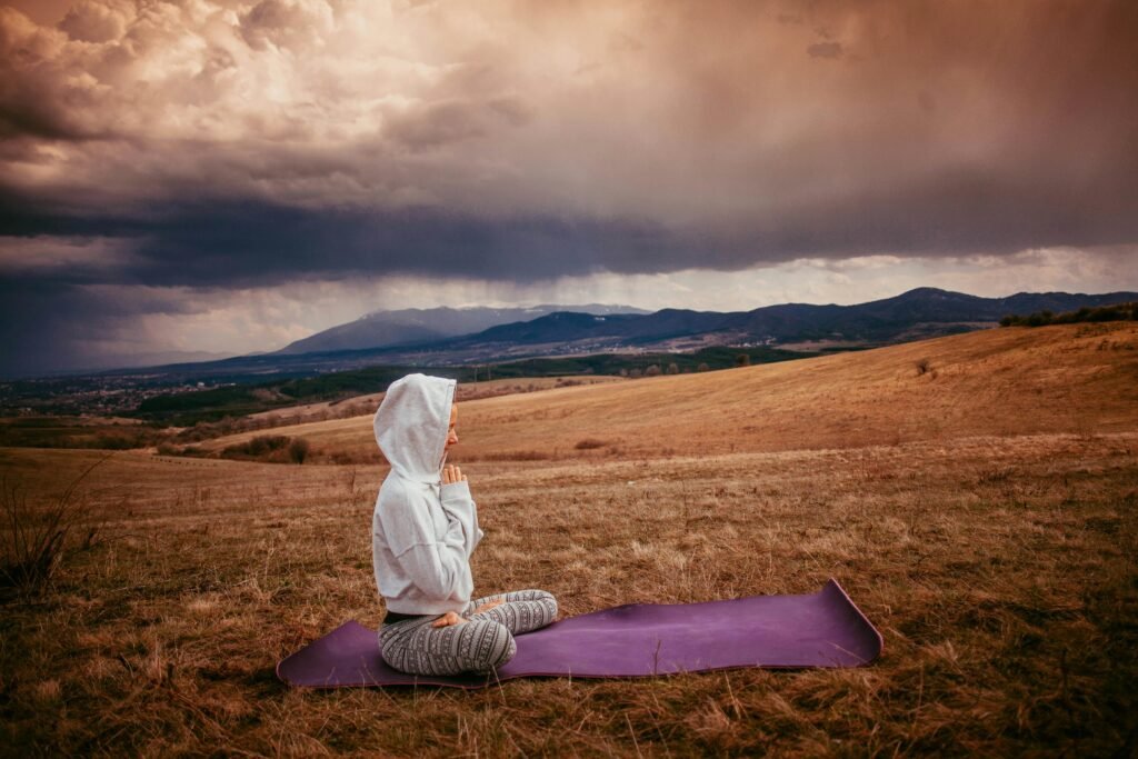 a woman in white hoodie sweater sitting on a yoga mat while meditating