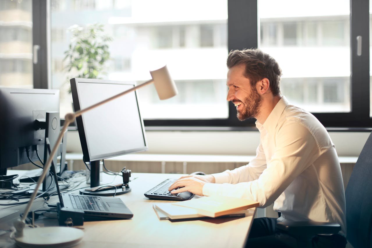 buisness search man-in-white-dress-shirt-sitting-on-black-rolling-chair-while-facing-black-computer-set-and-smiling